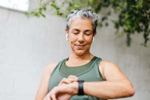 Female wearing airpods checks smartwatch before undertaking exercise.