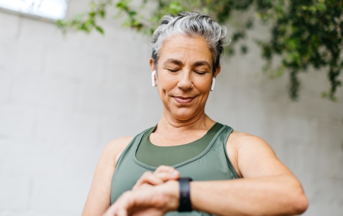 Female wearing airpods checks smartwatch before undertaking exercise.